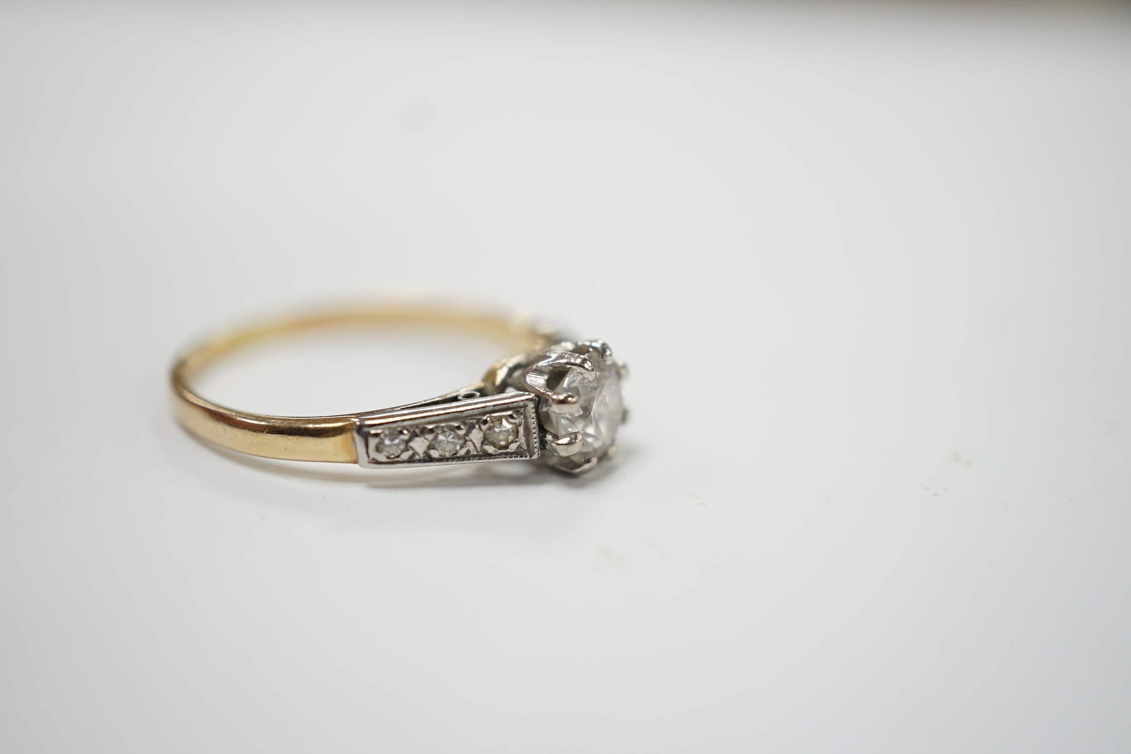 An early 20th century 18ct, plat. and single stone diamond set ring, with six stone diamond chip set shoulders, size O, gross weight 2.3 grams. Good condition.